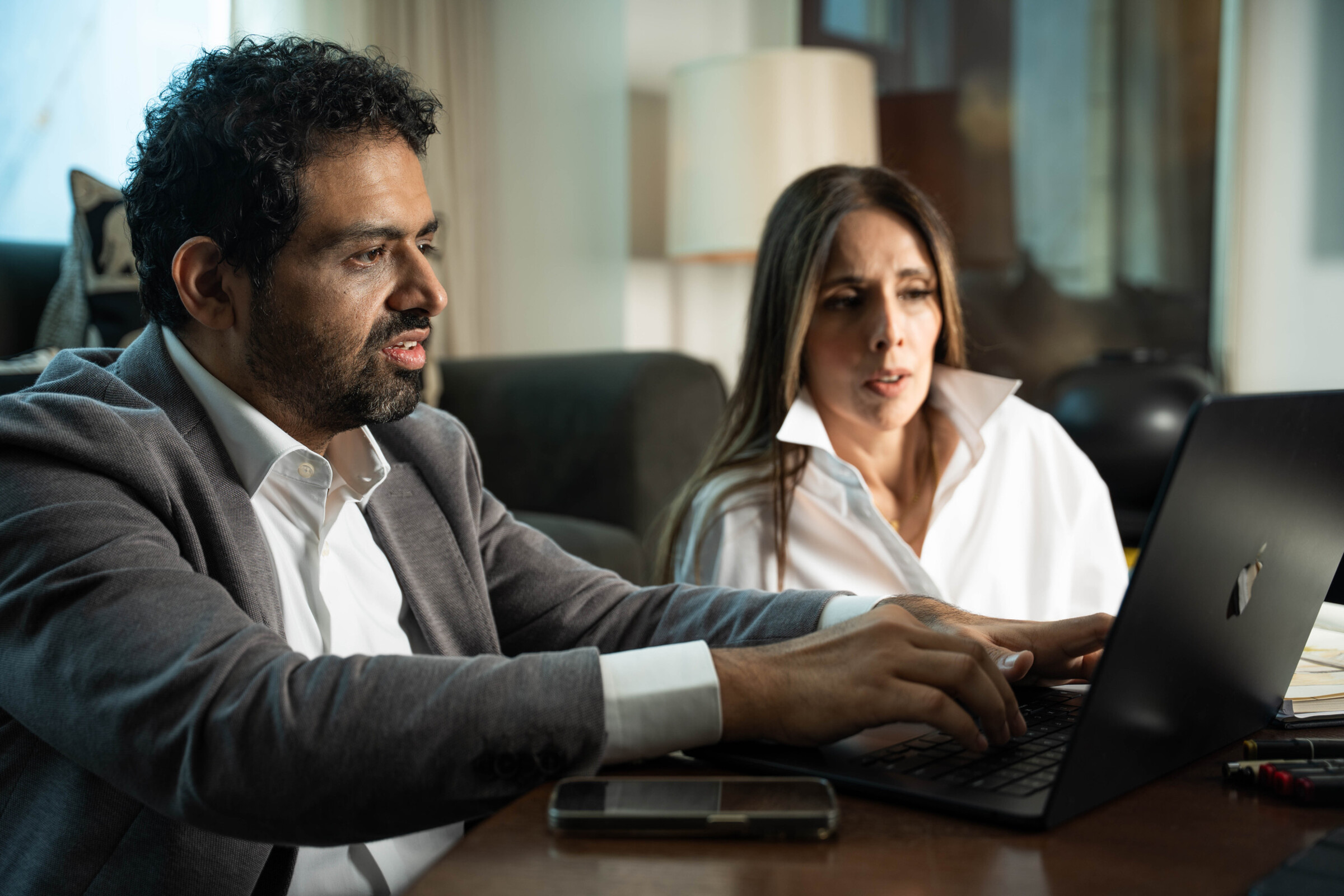 Bushra Khokhar and Tariq Ismail working through project numbers together at a laptop in the studio
