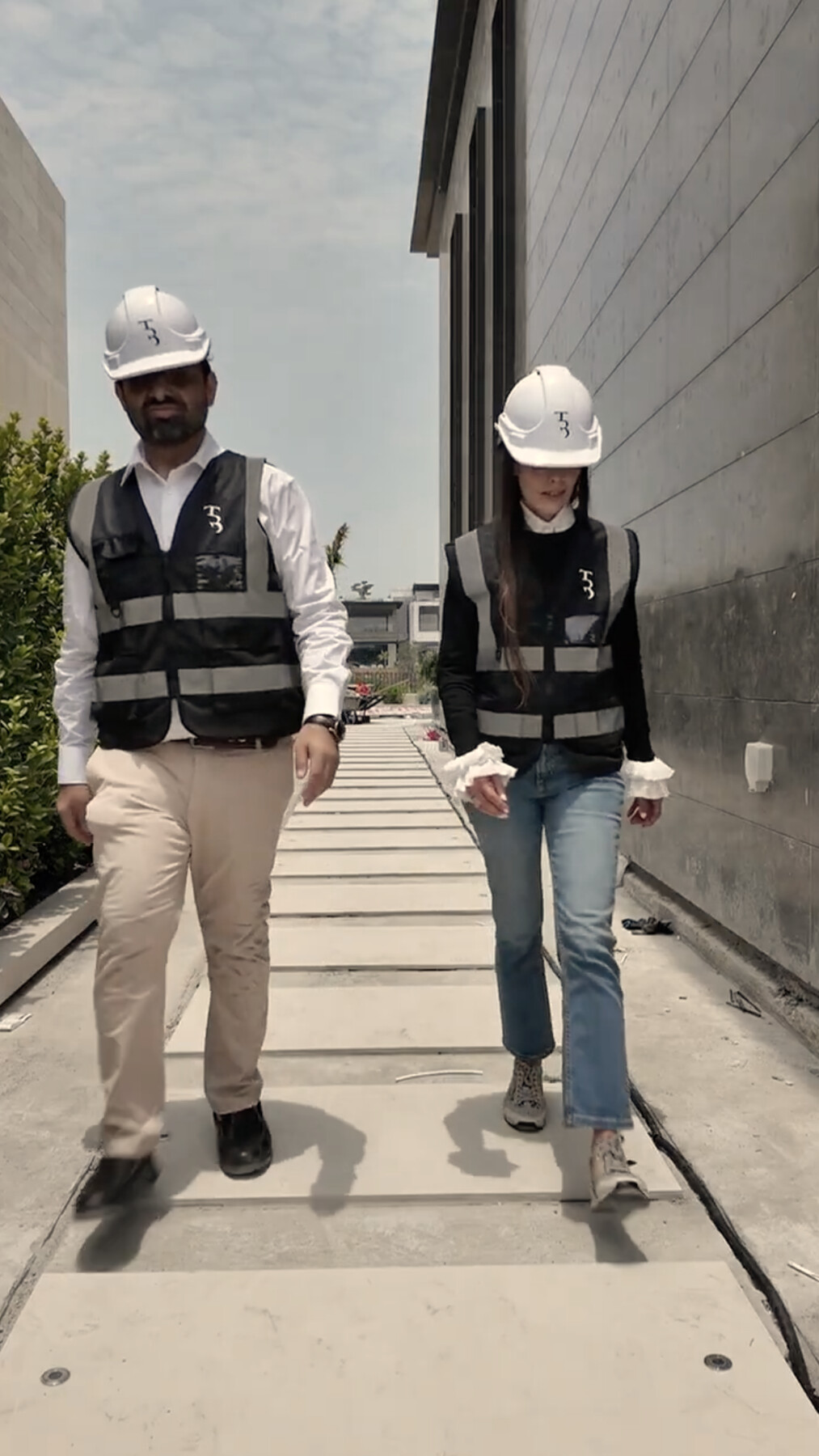 Bushra Khokhar and Tariq Ismail in True Build hard hats and hi-vis vests, walking a villa site in Dubai Hills